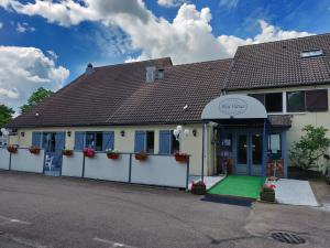 ein weißes Gebäude mit einem Zaun und einem Haus in der Unterkunft Contact Hotel Restaurant Bleu France - Eragny Cergy in Éragny