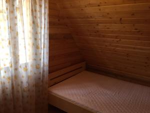 a small room with a bed in a wooden cabin at Domek przy plaży in Narty