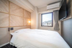 ein Schlafzimmer mit einem großen weißen Bett und einem Fenster in der Unterkunft Super Hotel Kobe in Kōbe