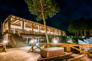 a building with a tree on a deck at night at Hotel Tajty in Giżycko