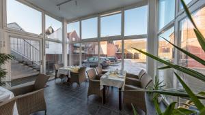 a dining room with tables and chairs and windows at Hotel Johann in Warendorf