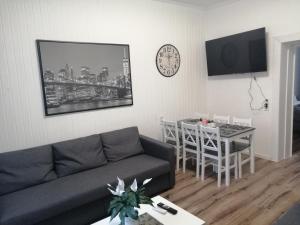 ein Wohnzimmer mit einer Couch, einem Tisch und einer Uhr in der Unterkunft Kölsche Wohnung 2C in Köln