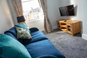 a blue couch in a living room with a television at Dovedale in Ashbourne
