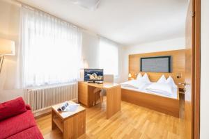 Sankt Martin am GrimmingにあるMAYER - Wirtshaus und Dorfhotelのベッドと赤いソファが備わるホテルルームです。