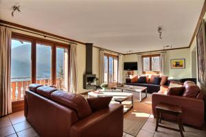 Elle comprend un salon doté d'un mobilier en cuir et d'une grande fenêtre. dans l'établissement CHALET - WIFI - SAINT JEAN D'AULPS - 10 Personnes - TAPTOP, à Saint-Jean-dʼAulps