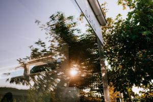 un letrero de la calle con el sol brillando a través de un árbol en Vier Häuser, en Norderney