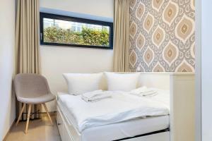 łóżko w pokoju z krzesłem i oknem w obiekcie die Strandvilla Nordwind w mieście Sellin