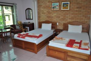 two beds in a room with a brick wall at An An Hotel in Rạch Giá