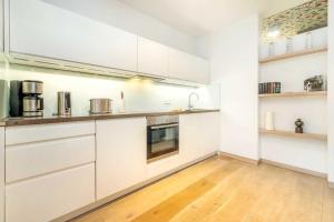 uma cozinha com armários brancos e piso em madeira em die Strandvilla Strandgut em Ostseebad Sellin