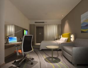 Holiday Inn Express Chengdu Jinniu, an IHG Hotel في تشنغدو: غرفة في الفندق مع سرير ومكتب مع لاب توب