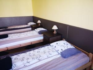 a room with three beds and two tables with lamps at Apartamenty Sokółka in Sokółka