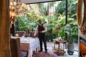 a man standing next to a table in a restaurant at The Residence in Johannesburg