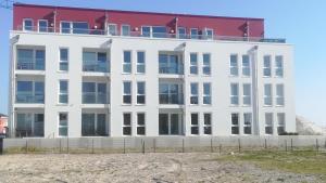 ein weißes Gebäude mit rotem Dach am Strand in der Unterkunft Residenz Bollwark Port Olpenitz in Kappeln