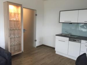 une cuisine avec des placards blancs et une porte avec des verres à vin dans l'établissement Residenz Bollwark Port Olpenitz, à Kappeln