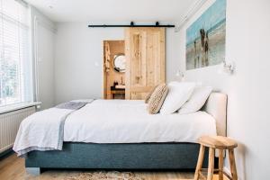 Schlafzimmer mit einem Bett mit weißer Bettwäsche und Kissen in der Unterkunft West 7 in Zandvoort