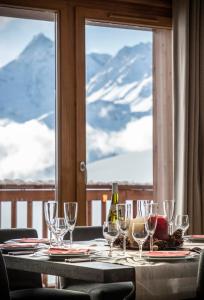 uma mesa com copos de vinho e vista para as montanhas em Residence Miravidi La Rosiere em La Rosière