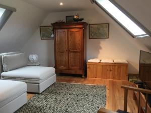a living room with a couch a chair and a cabinet at La Colline des Renards in Locmaria-Berrien