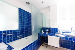 a blue tiled bathroom with a tub and a sink at The Albatroz Hotel in Cascais