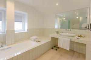 a bathroom with a tub and a sink and a mirror at The Albatroz Hotel in Cascais