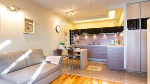 a living room with a couch and a kitchen at VacationClub - Gryfa Pomorskiego 77D Apartament 34B in Międzyzdroje