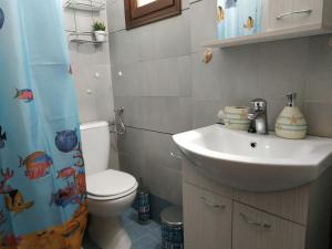 a bathroom with a sink and a toilet and a shower curtain at Παραθαλασσια στουντιο Μιχαλιας Sea view studio Michalias in Agia Marina Aegina