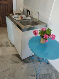 a kitchen with a sink and a table with flowers on it at Παραθαλασσια στουντιο Μιχαλιας Sea view studio Michalias in Agia Marina Aegina