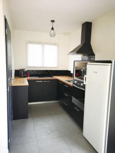 a kitchen with black cabinets and a white refrigerator at Maison neuve 66m2 Biscarrosse in Biscarrosse