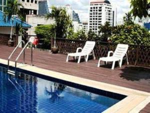 twee witte stoelen naast een zwembad bij King Royal Garden Inn in Bangkok