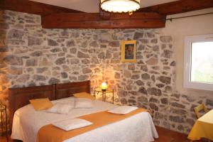a bedroom with a bed and a stone wall at Domaine de "Creva-Tinas" in Pouzols-Minervois