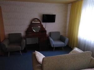 een kamer met 2 stoelen, een bureau en een spiegel bij Hotel Stadt Lügde in Lügde