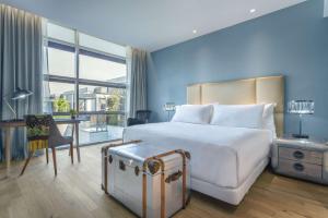 a hotel room with a large white bed and a desk at NH Collection Santiago Casacostanera in Santiago