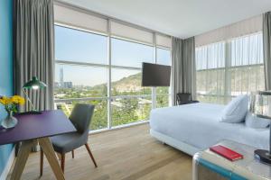 um quarto de hotel com uma cama, uma secretária e uma janela em NH Collection Santiago Casacostanera em Santiago