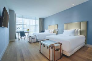 a hotel room with two beds and a table at NH Collection Santiago Casacostanera in Santiago