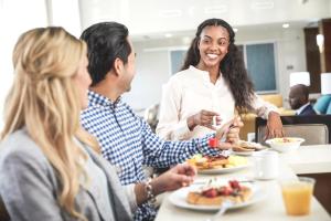 a group of people sitting around a table eating food at Staybridge Suites - Miami International Airport by IHG in Miami