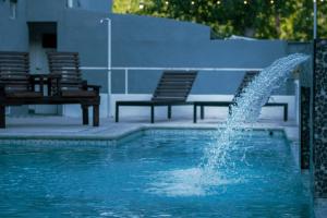 a fountain in a pool next to two benches at La Divina Pereza in San Rafael