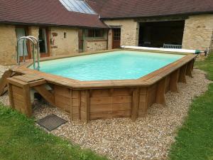 a large swimming pool with a wooden deck at 24H Le Mans - Les Haies Gite, near Le Mans Circuit in Coulans-sur-Gée