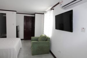 a living room with a couch and a television on a wall at Sand and Blue Seas in Negril