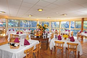 a dining room with tables and chairs and windows at Hotel Grand Canyon du Verdon in Aiguines