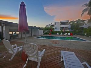 a patio with chairs and an umbrella and a pool at Sand and Blue Seas in Negril