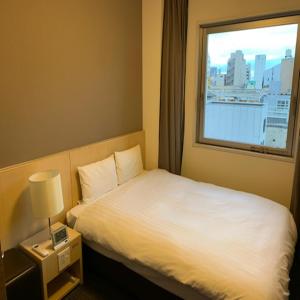 um quarto de hotel com uma cama e uma janela em Dormy Inn Kofu em Kofu