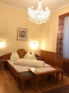 a bedroom with a bed and a chandelier at Cityhotel Ratheiser in Klagenfurt