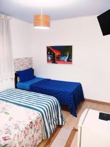 2 Betten in einem Zimmer mit blauer Bettwäsche in der Unterkunft Pousada TonaPraia in Florianópolis