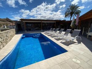 a swimming pool with lounge chairs next to a house at Anfi Tauro Golf Villa with private heated pool in Mogán