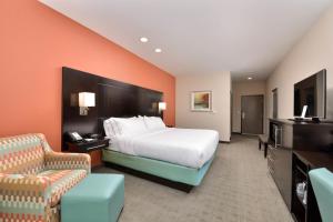 a hotel room with a bed and a chair at Holiday Inn Express & Suites Austin South, an IHG Hotel in Austin