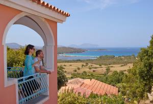 a man and a woman sitting on a balcony of a house at Residence Hotel Lu Nibareddu in San Teodoro