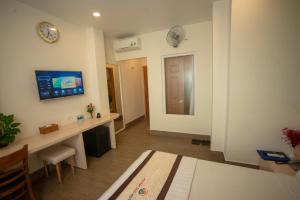 Habitación con escritorio y mesa con reloj en la pared. en Huynh Duc 2 Hotel en Cao Lãnh