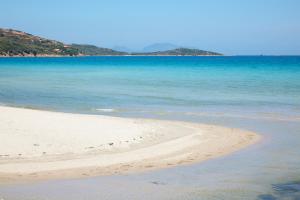 a beach with the ocean and mountains in the background at Residence Hotel Lu Nibareddu in San Teodoro