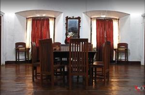 a dining room with a table and chairs and red curtains at Escolta's Homey Lodge in Vigan