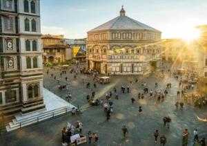 Un groupe de personnes marchant sur une place devant un bâtiment dans l'établissement Granduomo Charming Accomodation, à Florence