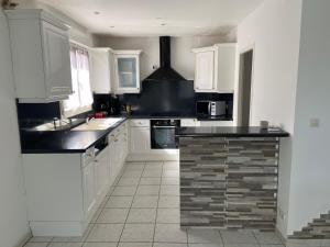 アネロンにあるMaison entière 4 lits 8 pl avec jacuzzi proche du safari de Peaugresの白いキャビネットと黒いカウンタートップを備えたキッチン